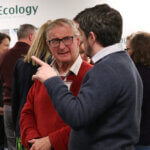 Two men speaking enthusiastically at the Ecology annual general meeting 2024.